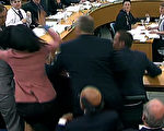 19日,傳媒大亨梅鐸（Rupert Murdoch）與兒子應邀到英國國會出席聽證會，會中有一名男子企圖攻擊梅鐸，遭梅鐸妻子鄧文迪（身穿粉紅色外套者）重揮一巴掌。（圖片來源：PARBUL/AFP）