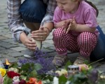 2011年7月24日，奧斯陸，一位帶著孩子的母親點燭悼念罹難者（ODD ANDERSEN / AFP ImageForum）