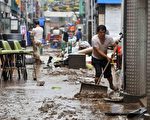 大水退後，韓國首爾東北的東豆川居民忙著清除淤泥。（AFP）