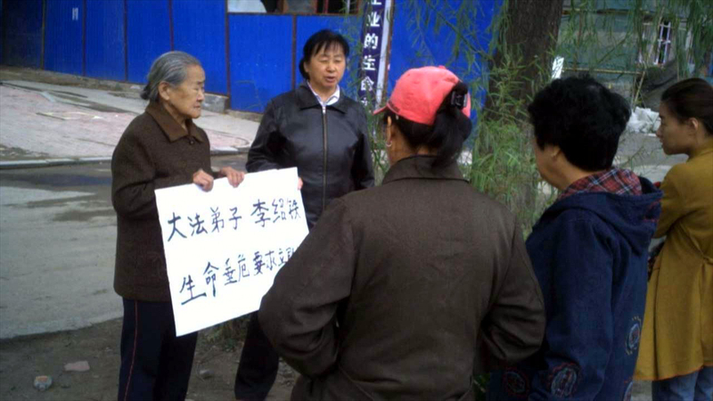 李紹鐵年近九旬的母親擧牌抗議，向中共要回自己的兒子。