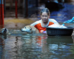 2011年10月15日，泰国洪水泛滥，曼谷郊区暖武里府水深及胸，一名泰籍女子抱着狗涉水而过。（ 图片来源：PORNCHAI KITTIWONGSAKUL／AFP）