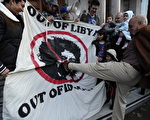 卡扎菲被击毙后，利比亚人欢欣鼓舞。图为一名男子一脚踢破了卡扎菲的画像。（CARL COURT/AFP/Getty Images）