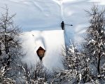 阿尔巴尼亚巴尔干地区，大雪已经将房屋覆盖，一名男子在清除积雪。摄于2012年2月14日。（GENT SHKULLAKU / AFP）