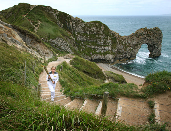 莉莎‧迪瓦恩(Lisa Devine)在侏罗纪海岸的著名景点多尔多门(Durdle Door)传递奥运圣火。(图片来源:Getty Images) 莉莎‧迪瓦恩(Lisa Devine)在侏罗纪海岸的著名景点多尔多门(Durdle Door)传递奥运圣火。(图片来源:Getty Images)