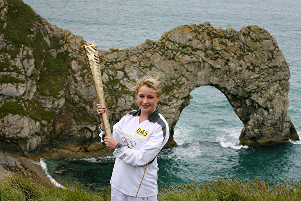 莉莎‧迪瓦恩(Lisa Devine)手举火炬在侏罗纪海岸的著名景点多尔多门(Durdle Door)。(图片来源:Getty Images) 莉莎‧迪瓦恩(Lisa Devine)手举火炬在侏罗纪海岸的著名景点多尔多门(Durdle Door)。(图片来源:Getty Images)