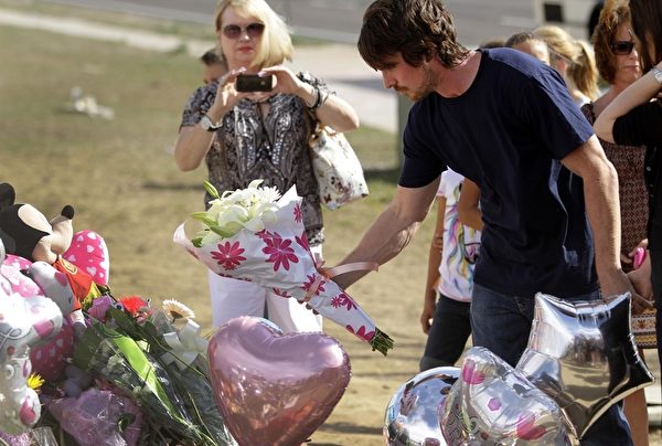 克里斯蒂安•贝尔（Christian Bale）和妻子一起献花悼念枪击案的死难者。(Joshua Lott/Getty Images)