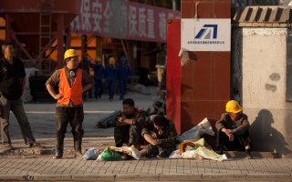 過去，中國許多基建工地工人要日日夜夜地工作，今天，許許多多工地處於停滯狀態，建築工人每天不過工作8個小時，甚至每週還有一天的休息。圖為2012年5月，北京市某工地工人在門口休息的場面。（Ed Jones/AFP/GettyImages）