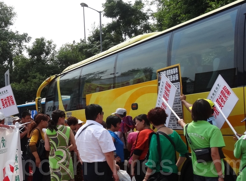 中港邊境落馬洲,中共惡黨團夥「香港青年關愛協會」穿綠衣製服的成員阻檔法輪功學員向來港遊客講真相。(市民提供)