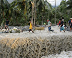 2012年12月5日，菲律宾遭遇强台宝发肆虐，孔波斯特拉省Andap村公路被洪水冲毁。图为居民用临时担架搬运一个男孩尸体。（TED ALJIBE/AFP）