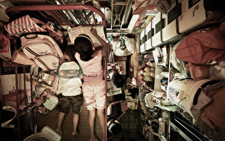 香港城市貧民窟，一對姊弟趴在床上，姊姊在寫字弟弟在睡覺。(Benny Lam / Society for Community Organizati / AFP)