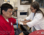 图：加州圣地亚哥亚太健康基金会近日在圣地亚哥中文学校为民众做免费肝炎检测，图为基金会义工Thuy Nguyen（右) 为中文学校成人学生李沐新抽血。（ 摄影：杨婕／大纪元）