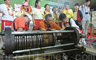 台北市長安國小小朋友使盡全力體驗操作芝麻油人工壓榨機。（攝影：鄭池南／大紀元）