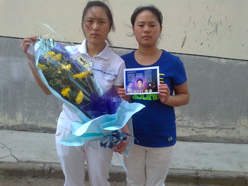 姐妹俩怀抱鲜花对爸爸满怀思念(图片来源:明慧网)