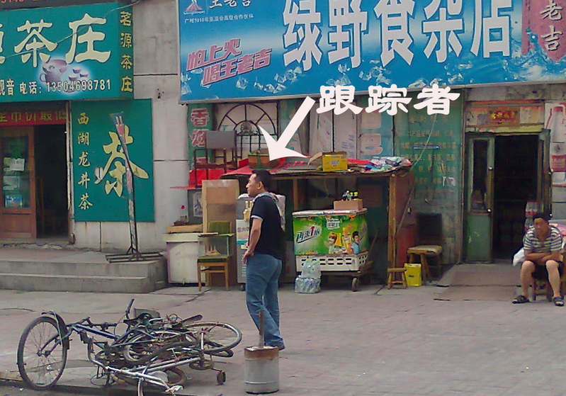 假装转身打电话的跟踪者(图片来源:明慧网)