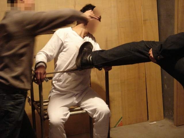 酷刑演示圖:警察對被固定著的雷明拳打腳踢。 (明慧網)
