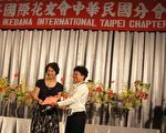 国际花友会中华民国分会会长林金癸颁发感谢状给示范演出的老师。（李容耕／大纪元）