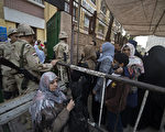 14日，埃及军人在开罗一个投票所外巡视、维持现场秩序，防止穆希的支持者破坏公投。（AFP）