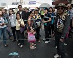 1月19日，泰國反政府民眾站在抗議營區所在地的勝利紀念碑前觀望，早前這裡被人投擲手榴彈。泰國反政府示威踏入第七天，隨著針對示威者的襲擊事件頻傳，暴力可能升級，與此同時曼谷受示威影響，遊客銳減，許多商家面臨裁員困境。（NICOLAS ASFOURI/AFP）