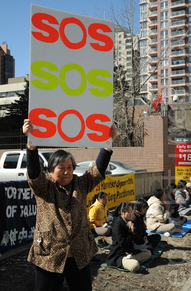 在喧囂的市中心第六大道的人行道上，黃金玲女士靜靜地高舉着SOS字樣的牌子，站在中共領事館前，向國際社會發出求救的呼聲：「救救我女兒」!（吳偉林/大紀元）