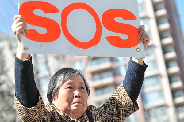 女兒絕食已經32天，生命垂危。黃金玲女士高舉SOS牌子，站在中共領事館前，向國際社會發出求救的呼聲：「救救我女兒」!（吳偉林/大紀元）