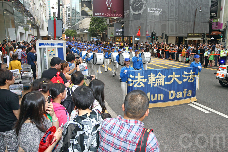 香港法轮功学员4月20日举行声势浩大的游行,纪念“四.二五”和平大上访15周年,大约八百人游行队伍沿着九龙的闹市区,途经多个大陆游客购物热点,吸引两旁的大批游客观看,许多人拿着手机和相机争相拍摄。(潘在殊/大纪元)