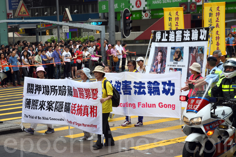 香港法轮功学员4月20日举行声势浩大的游行,纪念“四.二五”和平大上访15周年,大约八百人游行队伍沿着九龙的闹市区,途经多个大陆游客购物热点,吸引两旁的大批游客观看,许多人拿着手机和相机争相拍摄。(潘在殊/大纪元)
