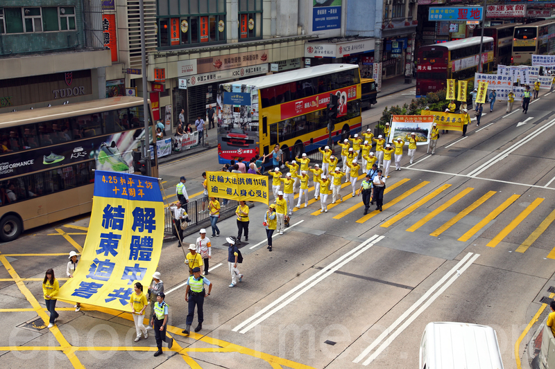 香港法轮功学员4月20日举行声势浩大的游行,纪念“四.二五”和平大上访15周年,大约八百人游行队伍沿着九龙的闹市区,途经多个大陆游客购物热点,吸引两旁的大批游客观看,许多人拿着手机和相机争相拍摄。(潘在殊/大纪元)