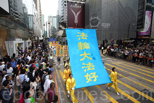 香港法轮功学员4月20日举行声势浩大的游行，纪念“四．二五”和平大上访15周年，大约八百人游行队伍沿着九龙的闹市区，途经多个大陆游客购物热点，吸引两旁的大批大陆游客观看，许多人拿着手机和相机争相拍摄。（潘在殊／大纪元）