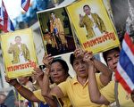2014年5月5日，泰王普密蓬（Bhumibol Adulyadej）登基64周年在华欣忘忧宫举行庆祝活动。图为泰国人拿着泰王照片，高喊“国王万岁”。（CHRISTOPHE ARCHAMBAULT／AFP／Getty Images）