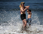 美國加州近日受到熱浪襲擊，本週氣溫可能創下歷史記錄。圖為13日，一對母子在舊金山海邊戲水。（Justin Sullivan／Getty Images）