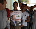 5月26日，埃及首都开罗，一位选民捧著前军方领导人施思将军的竞选海报，排队等著投票。观察家预测称，施思可能会击败另一候选人而当选。(Jonathan Rashad/Getty Images)