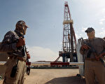 伊拉克遜尼派武裝分子已經奪取北方主要石油設施控制權，並繼續向全國各地推進，已迫使西方石油公司開始撤離員工。圖為兩位安全人員在伊拉克南方巴德拉（Badra）油田的一個鑽井平台的前方站崗。（AHMAD AL-RUBAYE/AFP/Getty Images）
