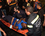黎巴嫩首都貝魯特於2014年6月23日晚間，發生一起汽車自殺炸彈攻擊事件。炸彈客駕車衝向正在咖啡廳觀看世足賽的球迷們，造成1死19傷。圖為救難人員從事故現場中，把一名受傷的女子抬上擔架送醫救治。（ANWAR AMRO/AFP）