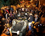 2014年7月9日，在加沙，人們圍繞著一部被以色列空襲擊中的汽車，一名記者被炸死。（Mustafa Hassona/Anadolu Agency/Getty Images）