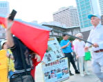 「愛國同心會」成員蕭勤（右）暴力阻撓新唐人亞太電視新聞部攝影與文字記者進行採訪。（新唐人亞太台）