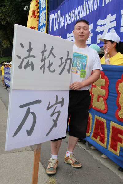 圖:大陸移民王先生自已製作了一個一人高的牌子,上面寫著「法輪功萬歲」。他認為法輪功是全球華人中最優秀的團體。(田園/大紀元)