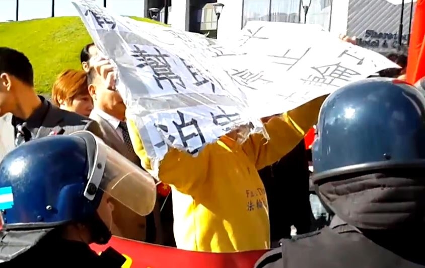 7月18日,中共駐阿根廷使館組織指使惡徒搶奪、損毀在習近平下榻酒店外請愿的阿根廷法轮功学员打出的紙板和橫幅。寫著「歡迎習近平 幫助停止迫害法輪功」的紙板被惡徒損壞,「習近平」、「迫害」字樣被惡徒摳壞不全。(大紀元)