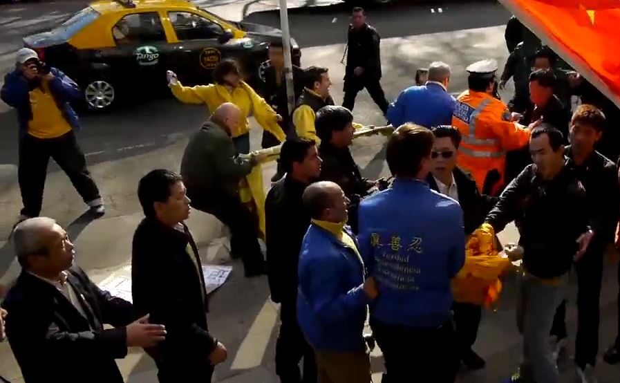 7月18日,就在車隊抵達前的半分鐘,在當地中共使館的指使下,當地華人超市協會及福建同鄉會組織一批惡徒突然動手暴力搶奪法輪功學員手中的橫幅與紙板。(大紀元)