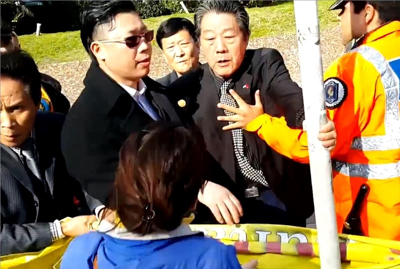 7月18日,就在習近平車隊抵達前的半分鐘,在當地中共使館的指使下,當地華人超市協會及福建同鄉會組織一批惡徒突然動手暴力搶奪法輪功學員手中的橫幅與紙板。(大紀元)