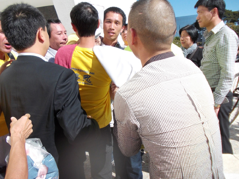 7月17日,中共爪牙於公共場合無理阻擋法輪功學員行動,搶走橫幅,圍毆學員。(大紀元)