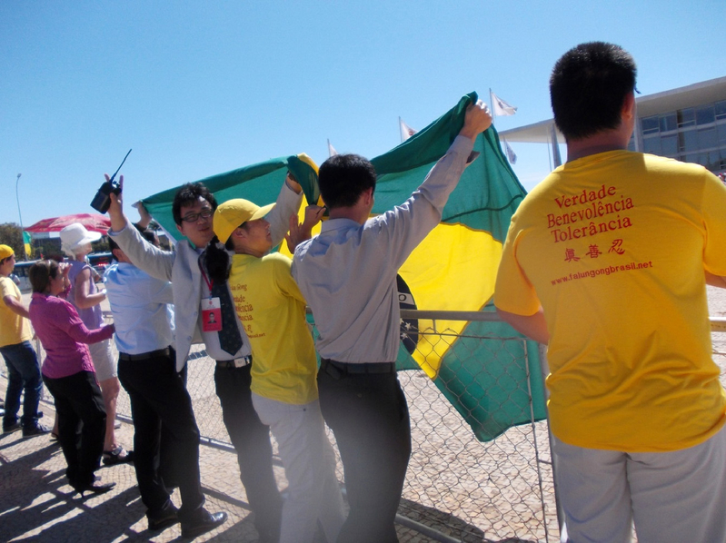 7月17日,法輪功學員們有秩序的於巴西總統府門前反對迫害,中共官員試圖蓋住抗議者卻毫無效果。(大紀元)
