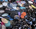 2014年9月28日，香港民众以雨伞阻挡警方喷洒的胡椒与水柱。示威者因为使用雨伞和保鲜膜包裹等简易防御，被外界称为“雨伞革命”。(Alex Ogle/AFP/Getty Images)