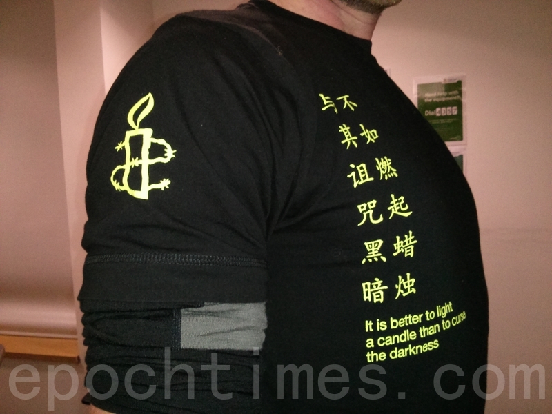 與會的國際大赦成員身穿寫有中文的T恤,與其詛咒黑暗,不如燃起蠟燭。(文華/大紀元)