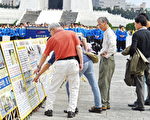 11月8日上午，近6千名部分法轮功学员，在台湾中正纪念堂自由广场前排出巨幅“佛光普照 礼义圆明”壮观图像。图为大陆游客认真读看法轮功真相图片。（孙湘诒/大纪元）