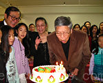 中华艺术协会圣诞派对上﹐团长林爱迪正在吹熄79岁生日蛋糕的蜡烛﹐其左为艺术总监陈玉律。(冯文鸾/大纪元)