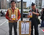 受害台商沈柏勝（左）在台北101大樓廣場免費送書給民眾。(賴月貴/大紀元)