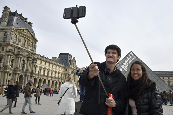 繼美國之後，歐洲多個著名景點亦宣佈禁止遊客使用自拍棒。圖為3月7日，遊客在巴黎盧浮宮前使用自拍棒。（DOMINIQUE FAGET/AFP） 