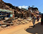 N图为2015年5月4日，加德满都北方的村落Trishuli，当地民众走过一整排在地震中毁坏的房子。(PRAKASH MATHEMA/AFP/Getty Images)