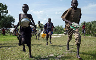 非洲有24個國家面臨糧食危機，為九十年代的2倍。圖為2014年7月5日，南蘇丹兒童衝進空投區，撿拾散落在地上的糧食。（Nichole Sobecki/AFP）