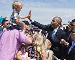 2015年7月21日，美國賓州匹茲堡國際機場，總統奧巴馬搭乘空軍一號抵達匹茲堡，在機場與2歲的歡迎者艾略特·賴利（左）擊掌，奧巴馬此行將前往退伍軍人全國大會發言，並繼續到紐約市上《喬恩·斯圖爾特每日秀》節目和參加民主黨籌款。（SAUL LOEB/AFP）